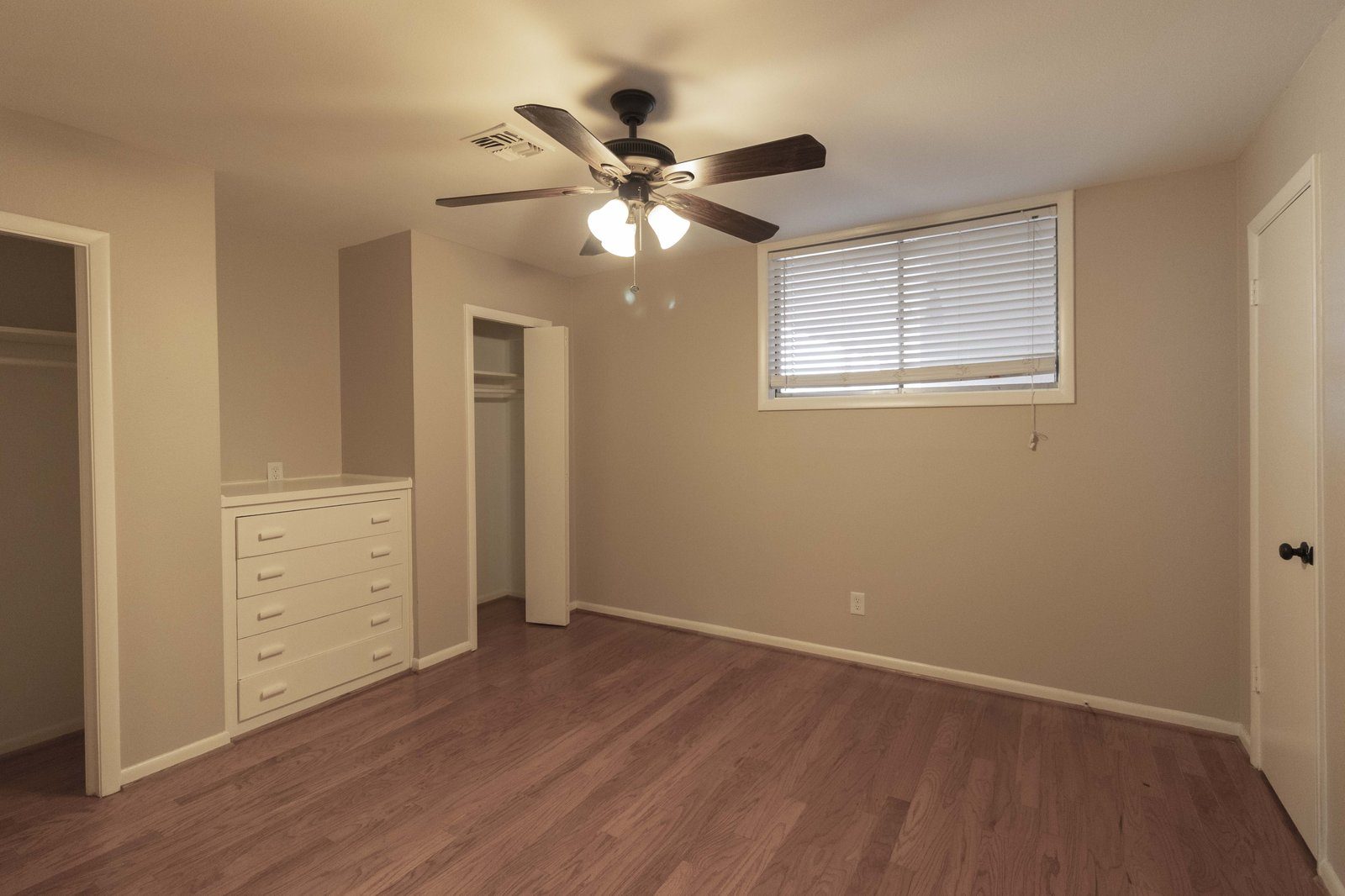 A refreshed unit interior with wood floors and the original built-in dresser retained.