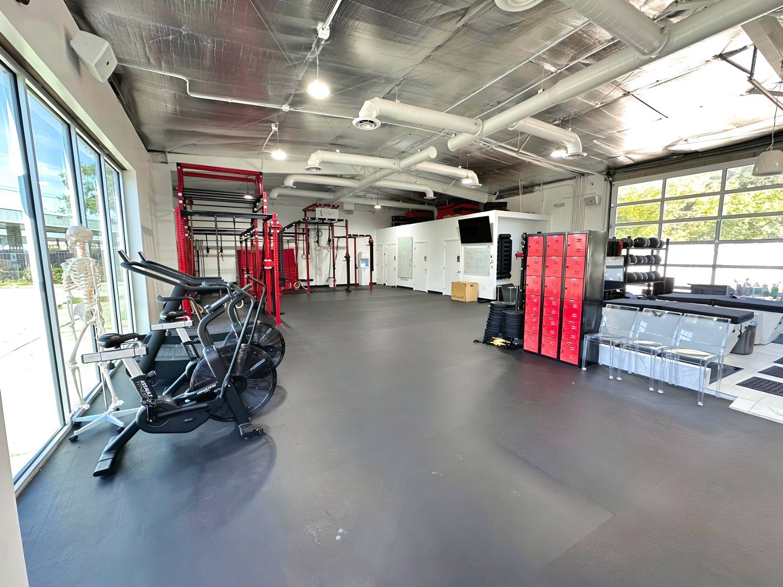 The training floor with exposed steel ductwork, full-height glass on both ends, and equipment ready for the day.